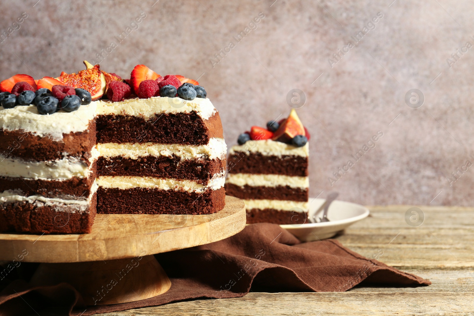 Photo of Delicious chocolate sponge cake with berries served on wooden table