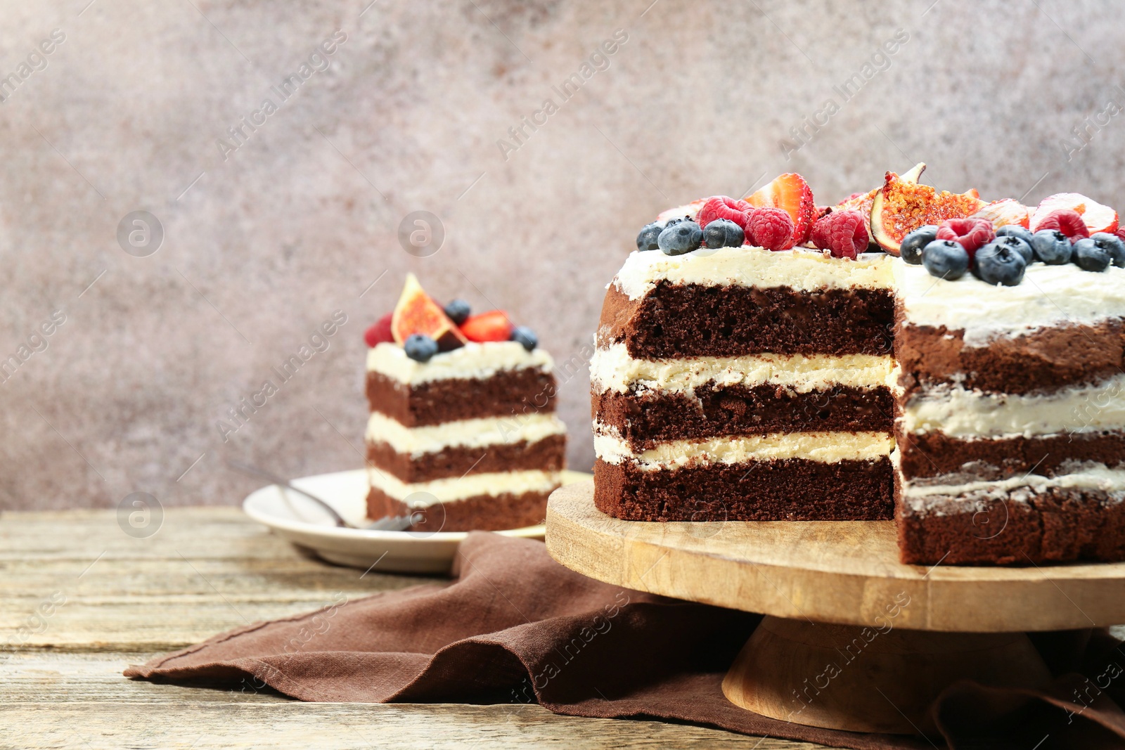 Photo of Delicious chocolate sponge cake with berries served on wooden table