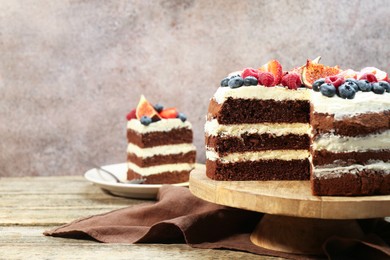 Photo of Delicious chocolate sponge cake with berries served on wooden table