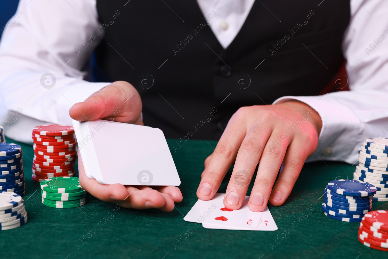 Photo of Professional croupier with playing cards at gambling table, closeup