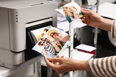 Photo of Woman with colorful photos near modern printer indoors, closeup