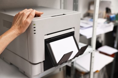 Photo of Woman using modern printer indoors, closeup. Printing house