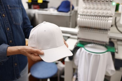 Photo of Woman with blank baseball cap for print indoors, closeup