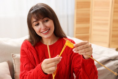 Beautiful woman knitting on sofa at home