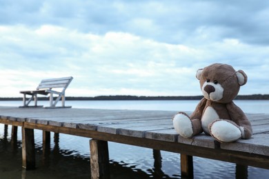 Lonely teddy bear on deck near river