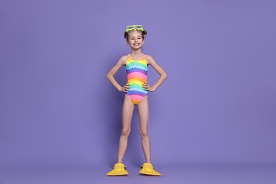 Photo of Happy girl in beachwear with diving mask and flippers on purple background