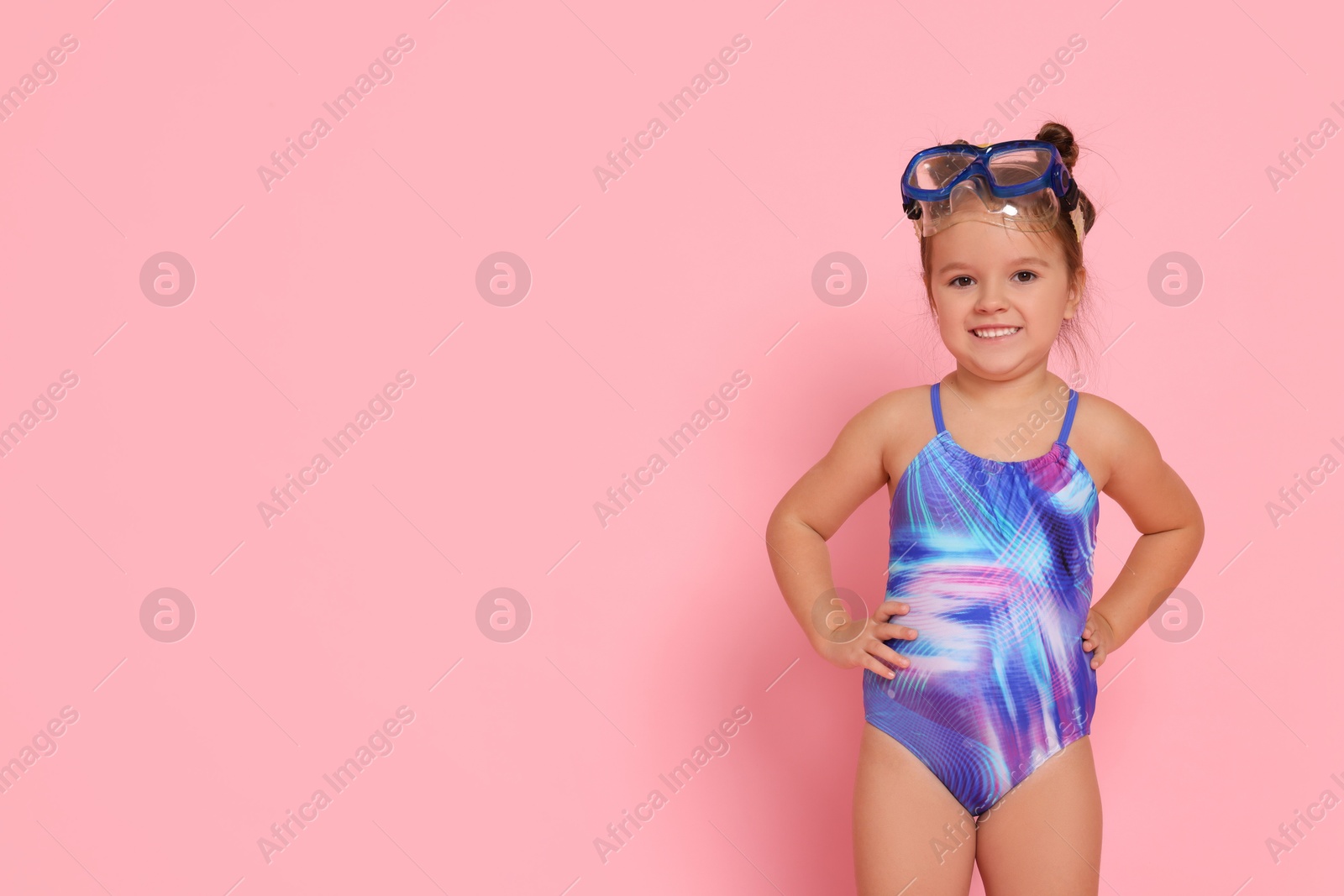 Photo of Cute little girl in swimsuit on light pink background. Space for text