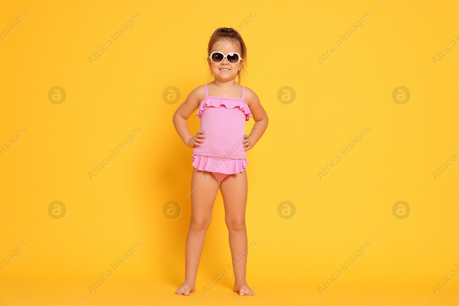 Photo of Cute little girl in swimsuit on orange background