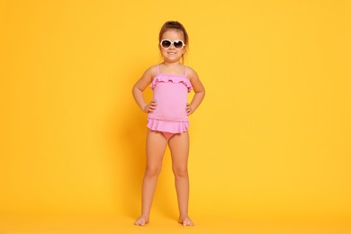 Photo of Cute little girl in swimsuit on orange background