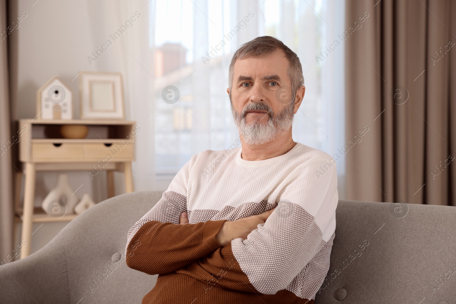 Photo of Mature man with crossed arms on sofa at home