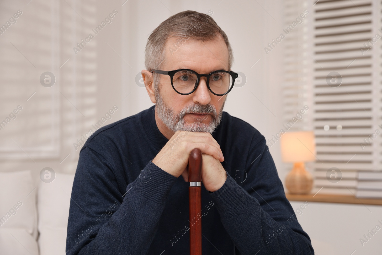 Photo of Mature man with walking cane at home