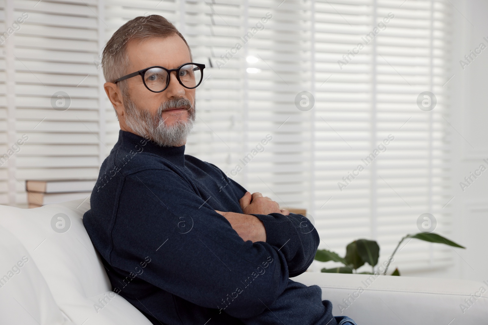 Photo of Mature man with crossed arms at home. Space for text