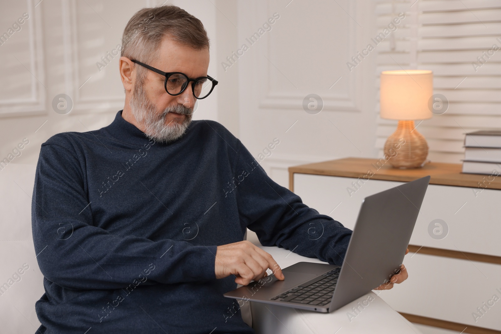 Photo of Mature man with laptop on sofa at home