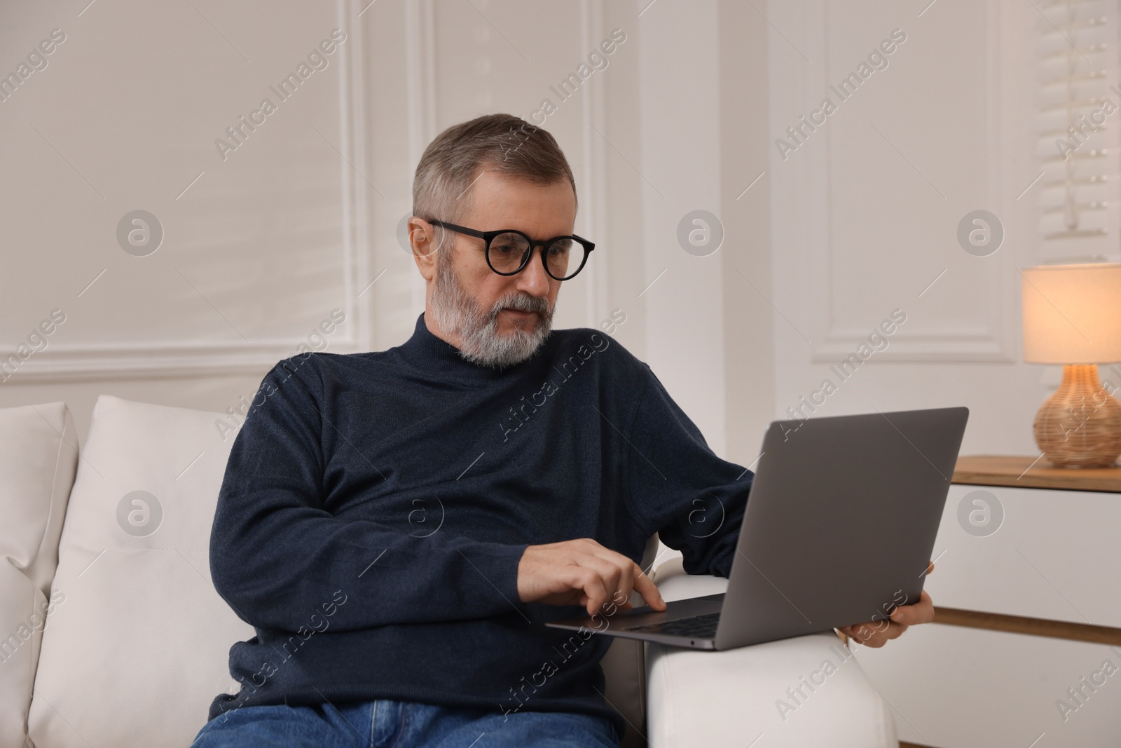 Photo of Mature man with laptop on sofa at home