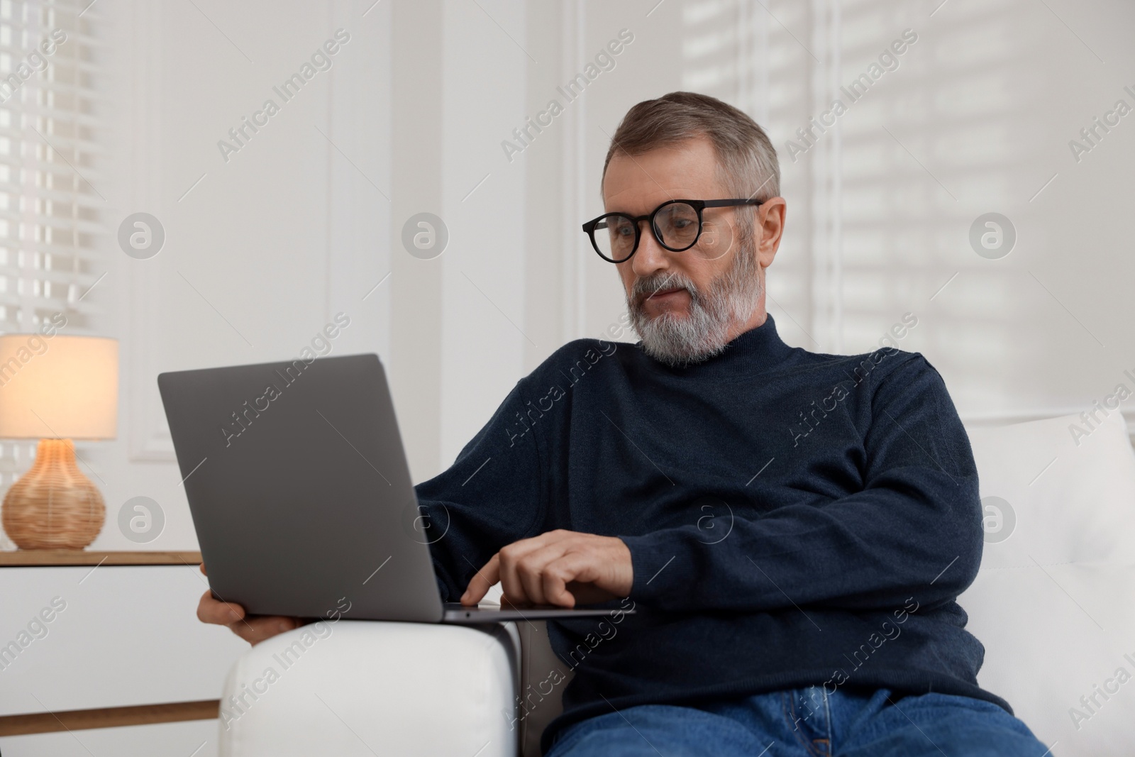 Photo of Mature man with laptop on sofa at home