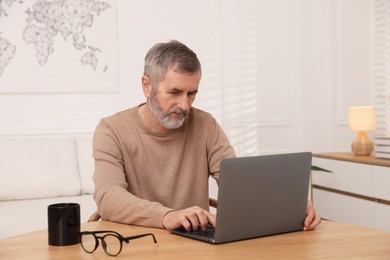 Mature man with laptop at table indoors