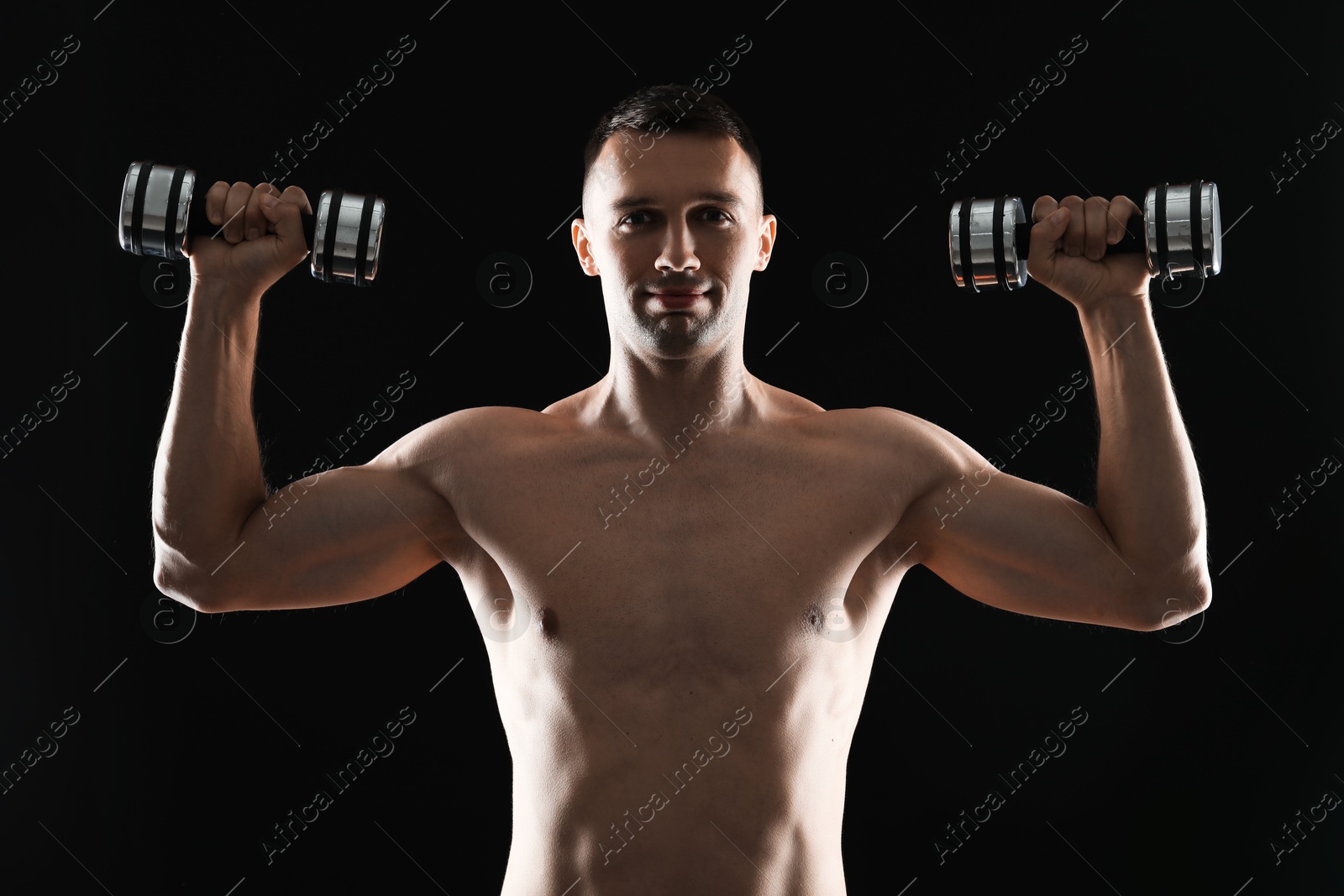 Photo of Man exercising with dumbbells on black background