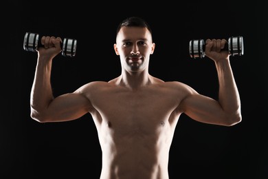 Photo of Man exercising with dumbbells on black background