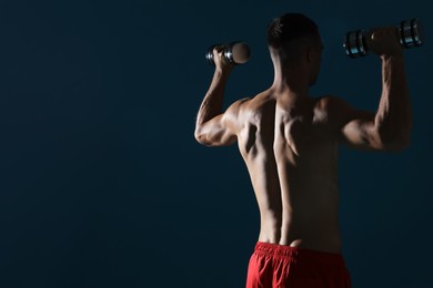 Photo of Man exercising with dumbbells on dark blue background, space for text