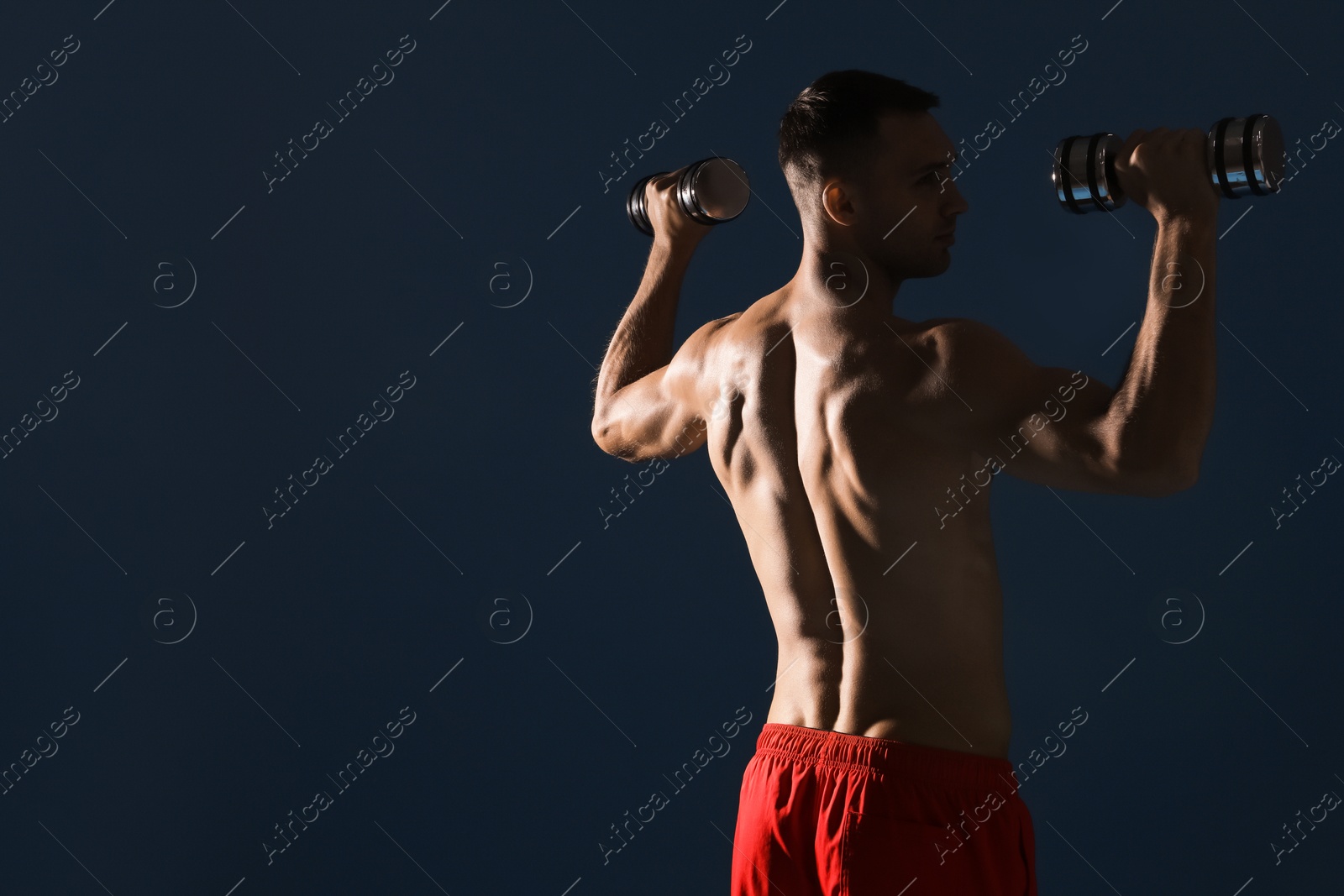 Photo of Man exercising with dumbbells on dark blue background, space for text