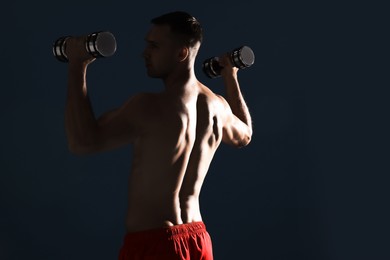 Photo of Man exercising with dumbbells on dark blue background