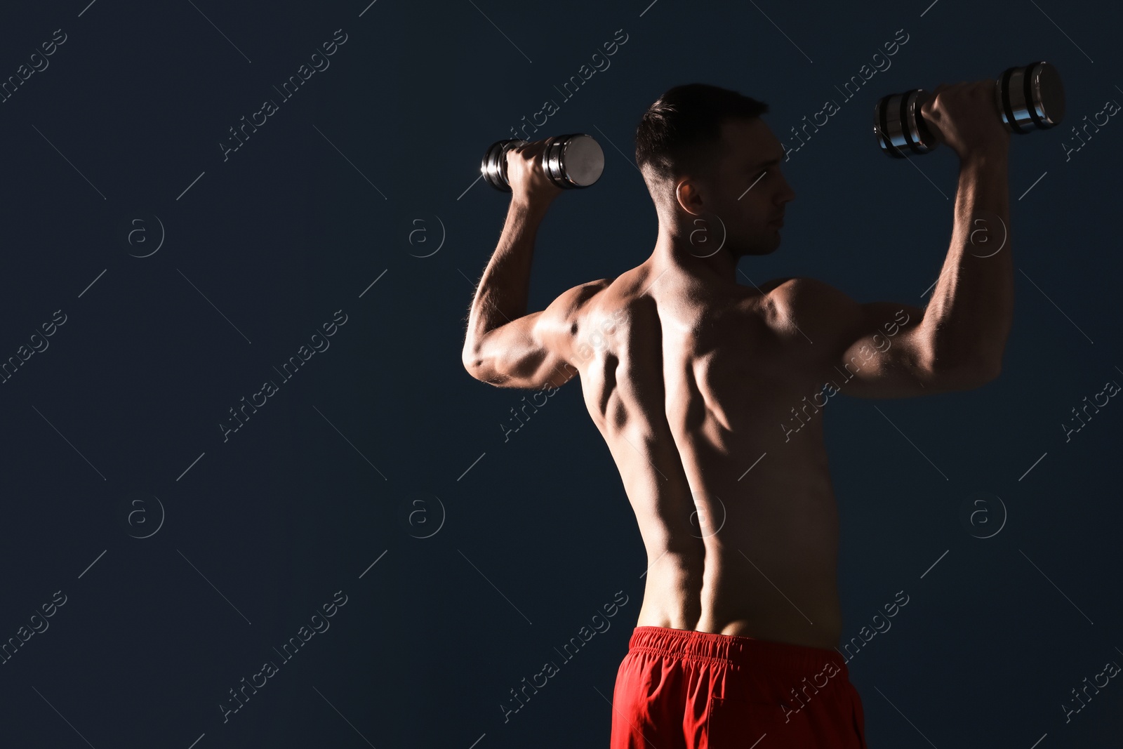 Photo of Man exercising with dumbbells on dark blue background, space for text