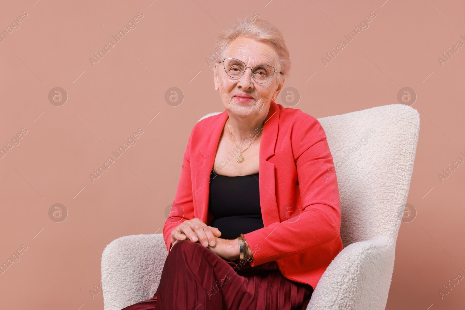 Photo of Senior woman in armchair on color background