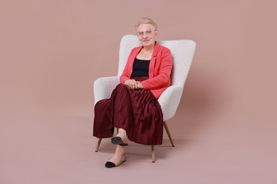 Photo of Senior woman in armchair on color background