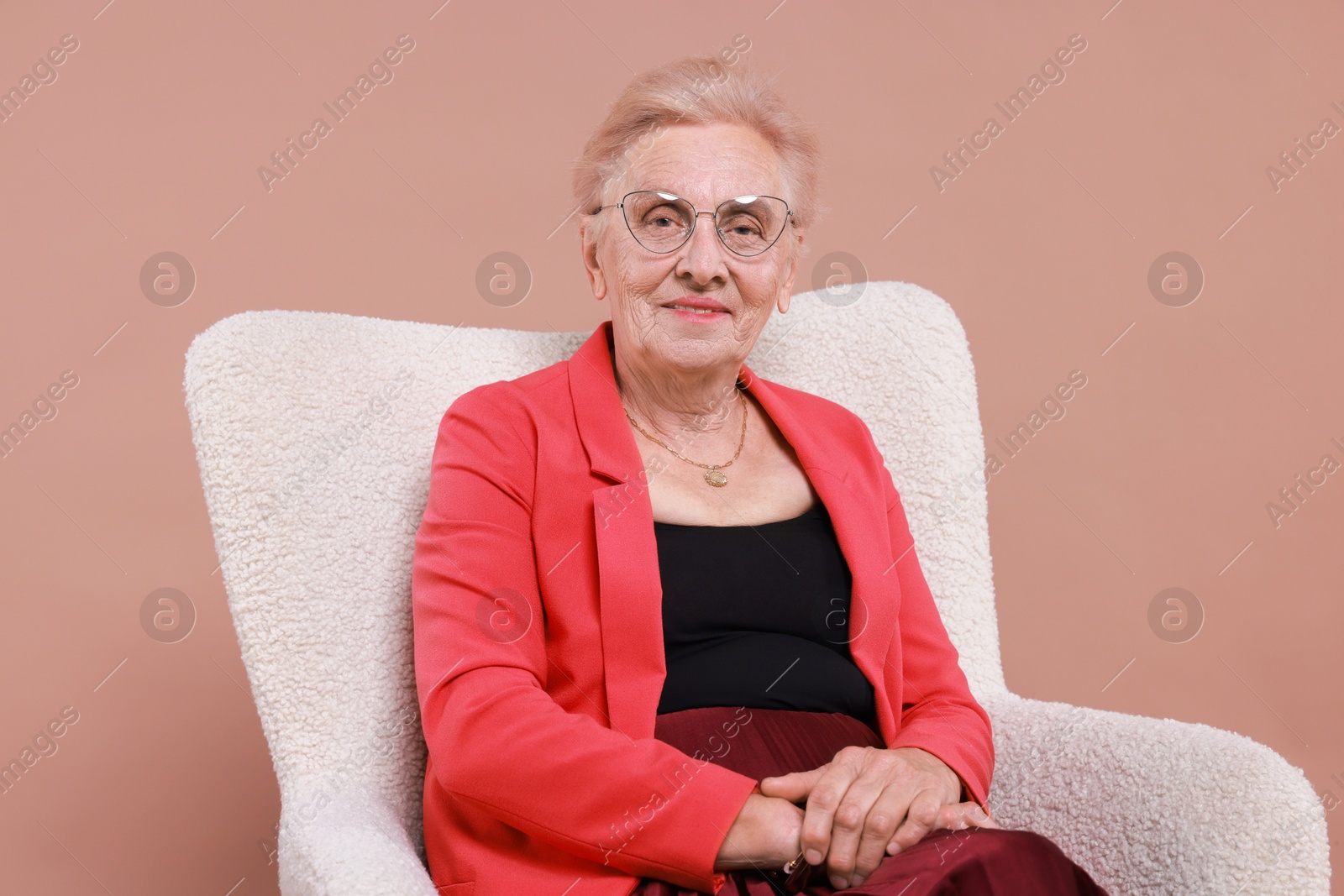 Photo of Senior woman in armchair on color background