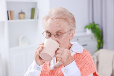 Photo of Senior woman with cup of drink at home