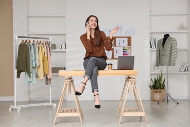 Photo of Fashion designer talking on smartphone in workshop