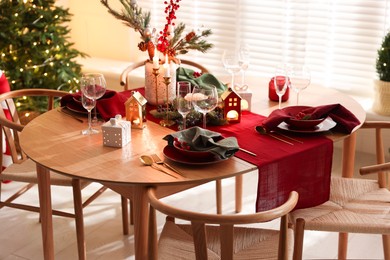 Photo of Christmas table setting with stylish dishware and festive decor indoors