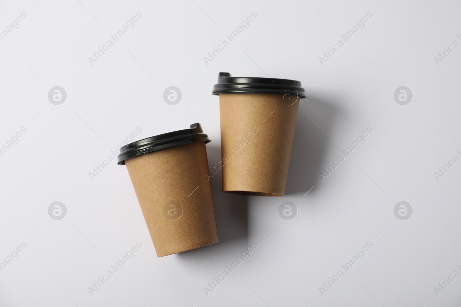 Photo of Paper cups with lids on white background, flat lay. Mockup for design