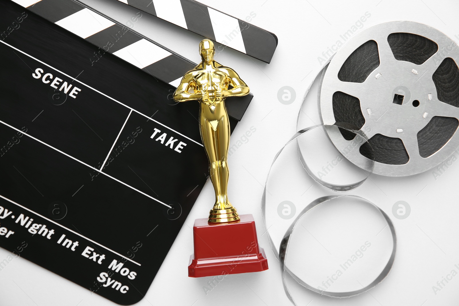 Photo of Golden trophy in shape of human figure, movie clapper and film reel on white background, top view