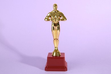 Photo of Golden trophy in shape of human figure on violet background