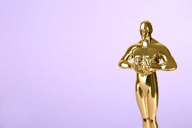 Photo of Golden trophy in shape of human figure on violet background, space for text