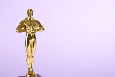 Photo of Golden trophy in shape of human figure on violet background, space for text