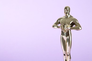 Photo of Golden trophy in shape of human figure on violet background, space for text