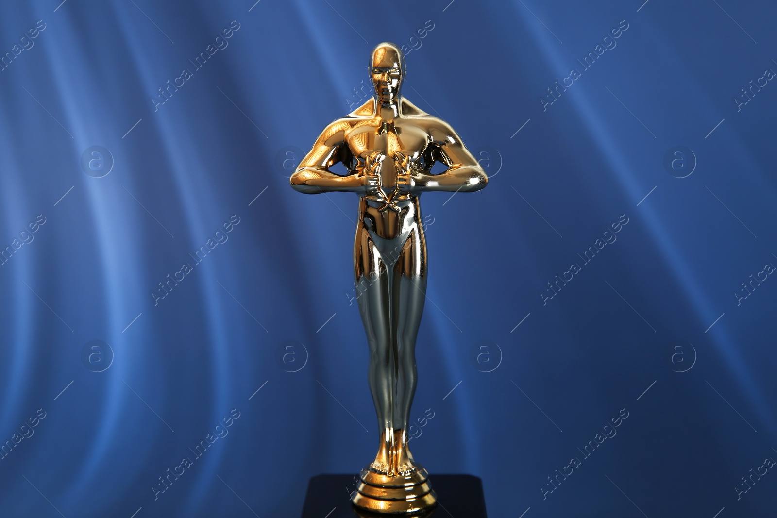 Photo of Golden trophy in shape of human figure on blue background