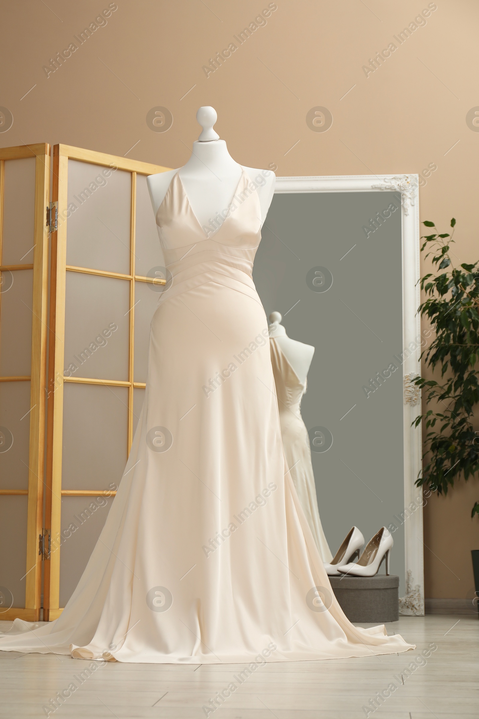 Photo of Beautiful wedding dress on mannequin and shoes in boutique