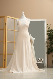 Photo of Beautiful wedding dress on mannequin and shoes in boutique