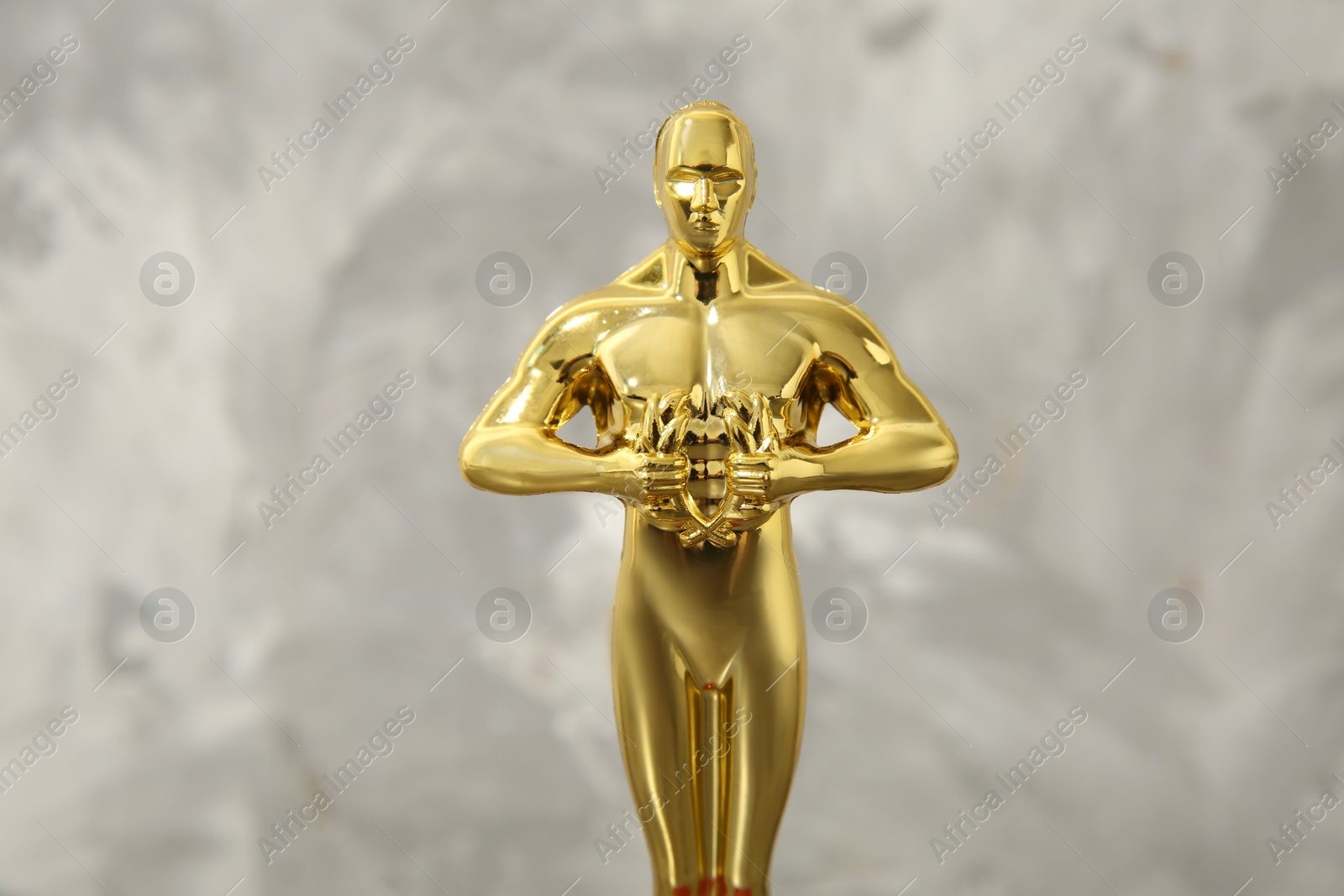 Photo of Golden trophy in shape of human figure against blurred gray background