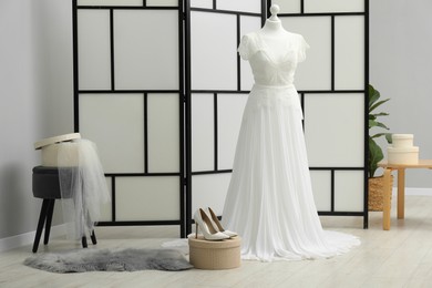 Photo of Beautiful wedding dress on mannequin and shoes in boutique