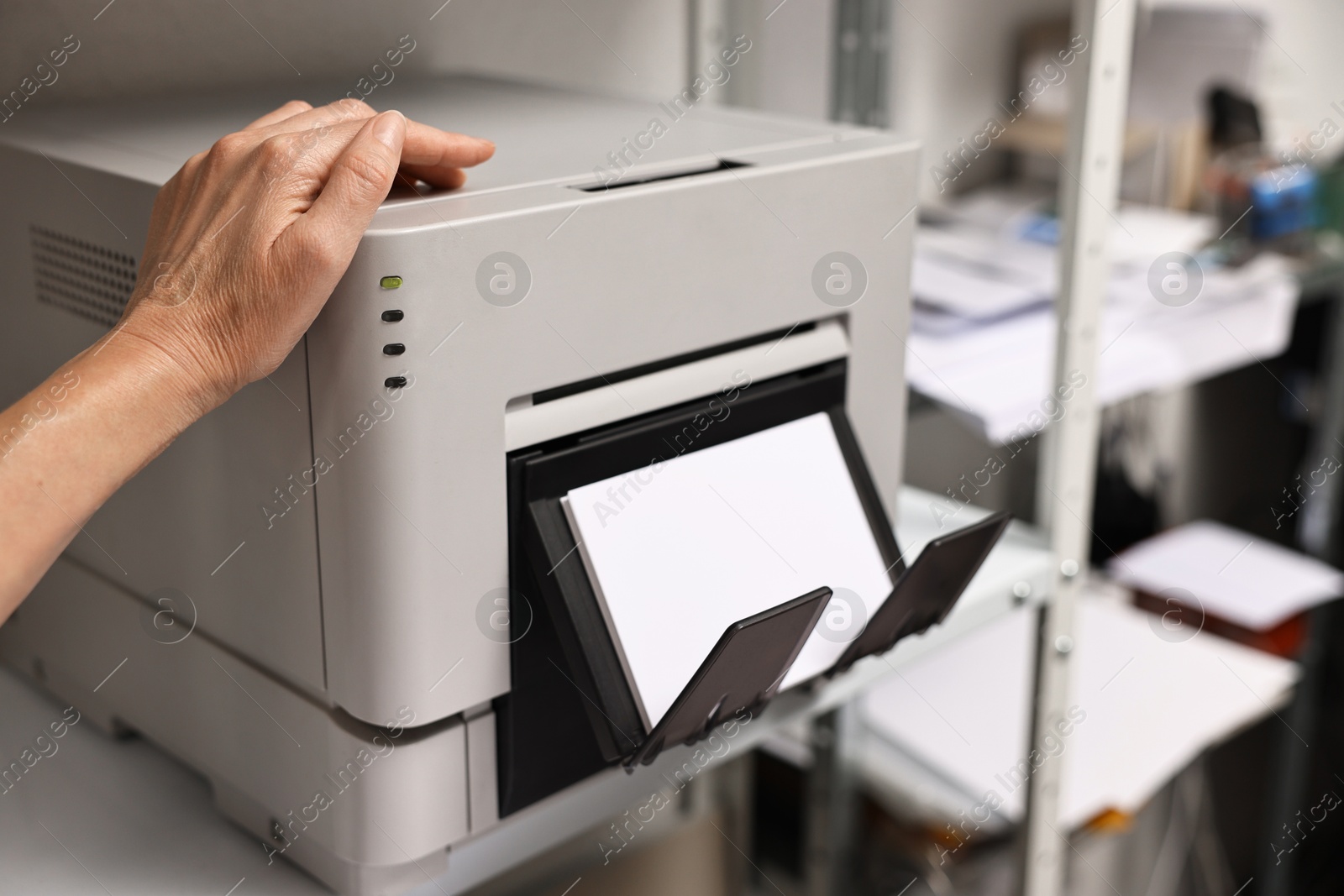 Photo of Woman using modern printer indoors, closeup. Printing house