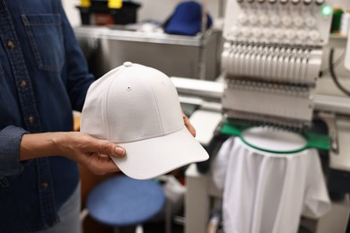 Photo of Woman with blank baseball cap for print indoors, closeup