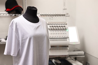 Photo of Mannequin with blank T-shirt for print and modern embroidery machine indoors