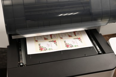 Photo of Modern printer with printed wedding invitation cards indoors, closeup. Printing house