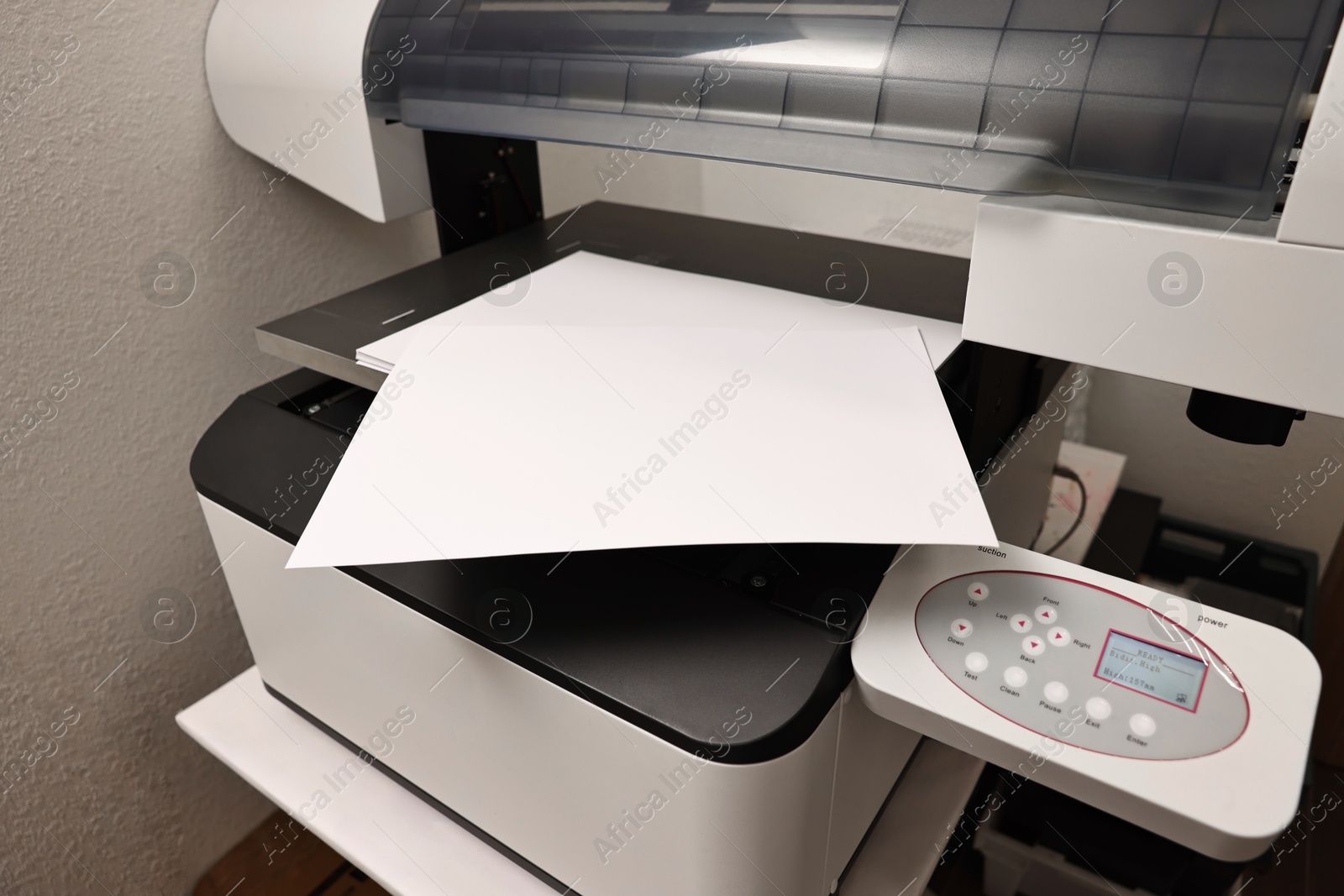 Photo of Modern printer with paper indoors, closeup. Printing house