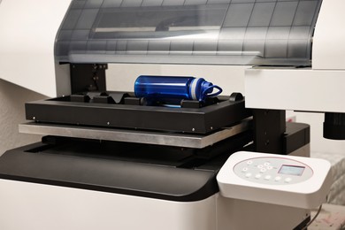 Photo of Modern printer and empty bottle indoors, closeup