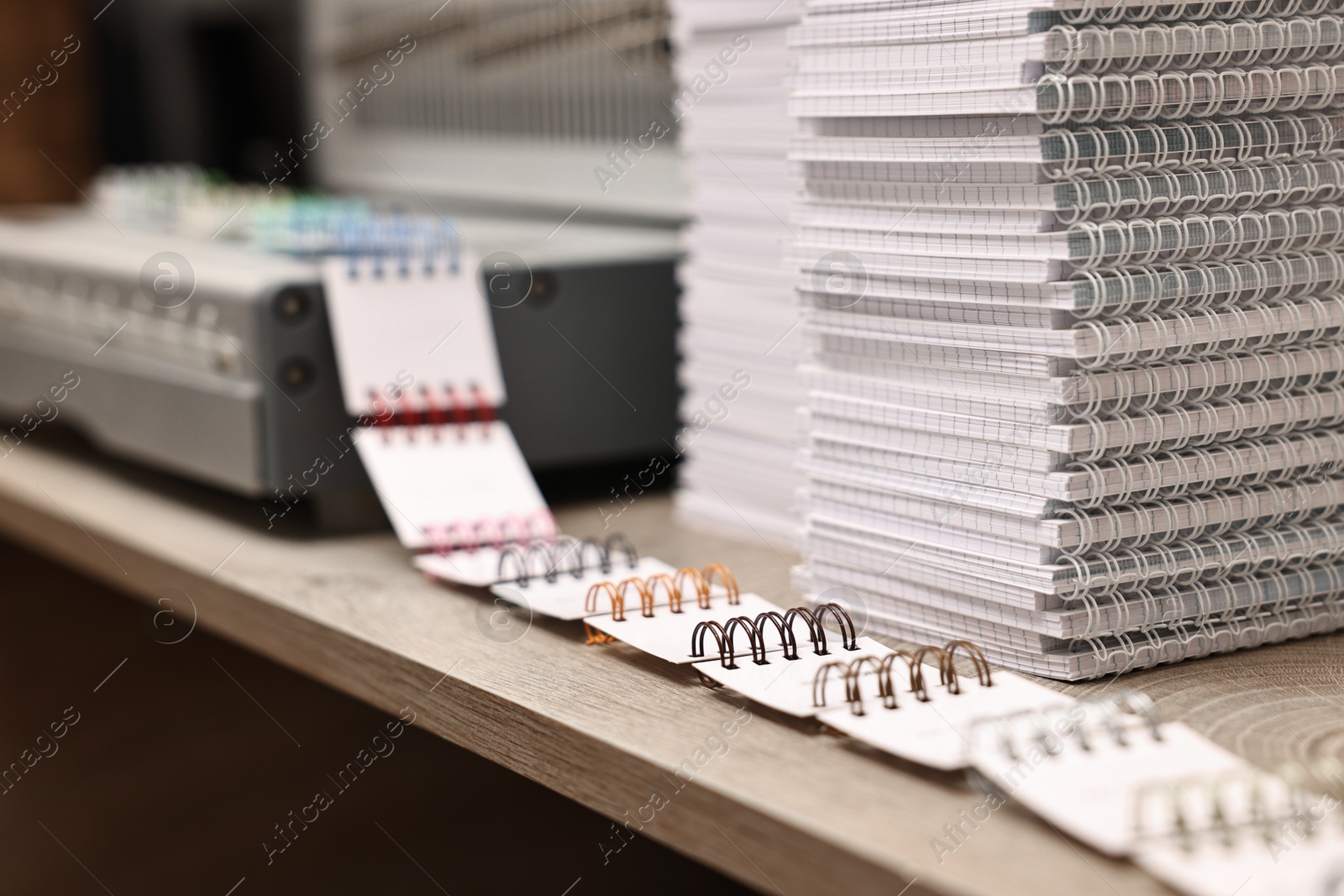 Photo of Stacks of notebooks and double loop wire binding spines on wooden table indoors, closeup